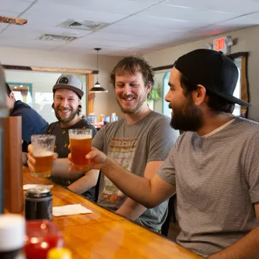 A group of men sitting at the bar drinking beer.