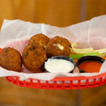 A basket of food with some dipping sauces.