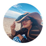 A woman sitting on the beach wearing a hat.