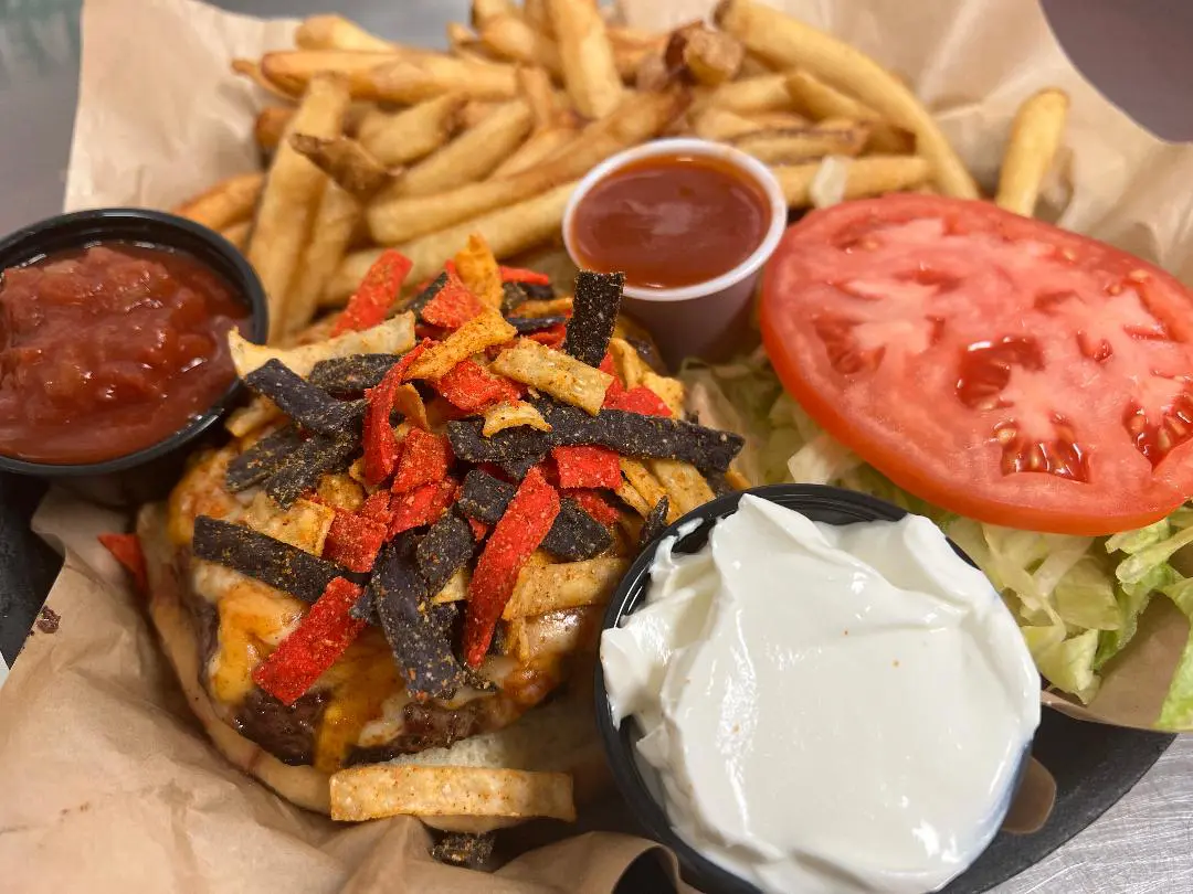 A hamburger with fries and tomato on the side.